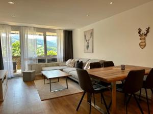 een woonkamer met een bank en een tafel met stoelen bij Apartment BERGseetraum - Bergblick, neu renoviert, gemütlich, familienfreundlich in Schliersee