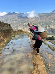 una mujer parada en una colina mirando un cuerpo de agua en Surelee Homestay en Sa Pa