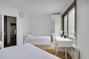 ein weißes Schlafzimmer mit einem Bett und einem Schreibtisch in der Unterkunft Pick A Flat's Apartment in Montparnasse - Rue Vercingétorix in Paris