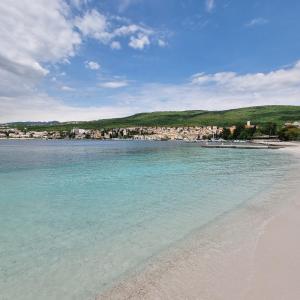 a beach with blue water and a town in the background at Villa Margarita in Selce
