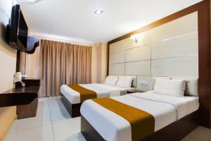 um quarto de hotel com duas camas e uma televisão de ecrã plano em Sejati Hotel em Sitiawan