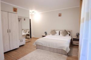 Dormitorio blanco con cama blanca y espejo en Casa Isabela en Putna