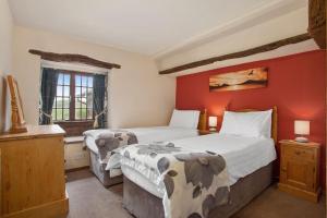 um quarto com 2 camas e uma parede vermelha em The Coppermines Mountain Cottages - Sawyers, Millrace, Pelton Wheel, Sleeps 16 em Coniston