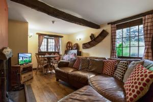un soggiorno con un divano in pelle e una televisione di The Coppermines Mountain Cottages - Sawyers, Millrace, Pelton Wheel, Sleeps 16 a Coniston