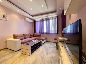 uma sala de estar com um sofá e uma televisão de ecrã plano em Апартамент Чаролит / Apartment Charoite em Burgas