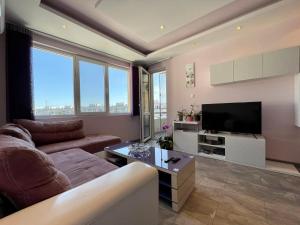 een woonkamer met een bank en een flatscreen-tv bij Апартамент Чаролит / Apartment Charoite in Boergas