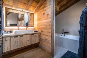 a bathroom with a sink and a tub and a mirror at Chalet Arpitania - OVO Network in La Clusaz