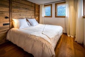 Un dormitorio con una gran cama blanca y una ventana en Chalet Arpitania - OVO Network, en La Clusaz