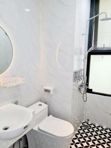 a white bathroom with a toilet and a sink at Happy House Homestay 2 in Hue