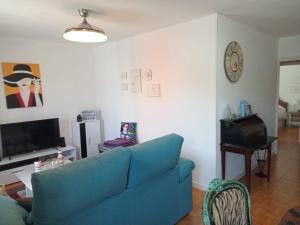een woonkamer met een blauwe bank en een tv bij Coquetty Housing In Santander Bay in El Astillero