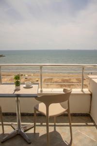 a table and chair on a balcony overlooking the ocean at Wave Beachfront Apartments in Durrës