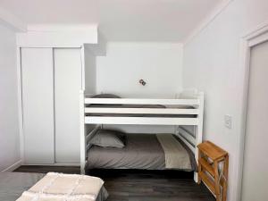 Ce lit superposé blanc se trouve dans une chambre blanche. dans l'établissement Paradis - Hyper Centre, a deux pas de la Mer !, à Canet
