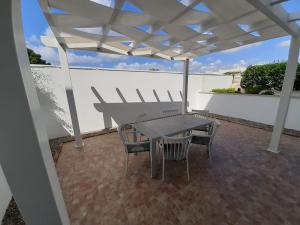 a table and chairs under a white umbrella on a patio at Appartamento MaRi con piscina in Torre Lapillo
