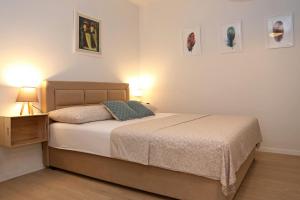 a bedroom with a bed and two lamps and pictures on the wall at Studio CAMINO with parking in Zadar