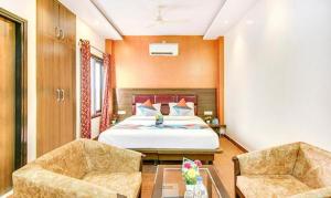 a hotel room with a bed and two chairs at FabHotel The Gayatri Palace in Lucknow