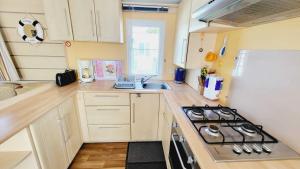 a small kitchen with a stove and a sink at Le Costa Gloria - Sud Nantes Camping de la Prairie in Saint-Hilaire-de-Riez