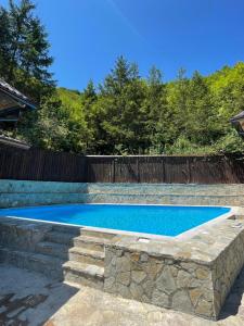 a swimming pool with a stone retaining wall next to a fence at Inas & Lemia Forrest Homes with Outdoor Swimming Pool in Bihać