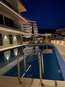 a swimming pool in front of a building at night at Elia in Bečići