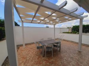a patio with a table and chairs under a pergola at Appartamento MaRi con piscina in Torre Lapillo