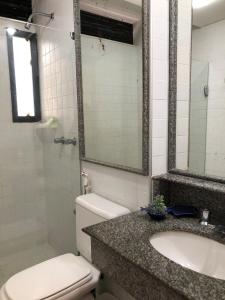 ein Badezimmer mit einem WC, einem Waschbecken und einem Spiegel in der Unterkunft Studio encantador com vista mar in Salvador