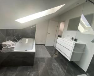 a white bathroom with a tub and a sink at Ferienwohnung im Allgäu in Bernbeuren