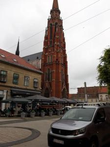 un'auto è parcheggiata di fronte a una torre alta di Apartman Slavonija 2 a Osijek