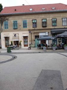 un edificio con una strada con un edificio con tavoli e ombrelloni di Apartman Slavonija 2 a Osijek