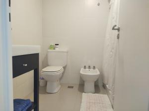 a white bathroom with a toilet and a sink at Suitte in Bahía Blanca