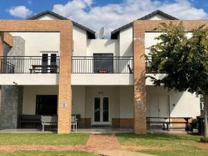 a white building with a balcony and a tree at Executive Modern Apartment in Fourways