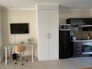 a kitchen with a table and a black refrigerator at Executive Modern Apartment in Fourways