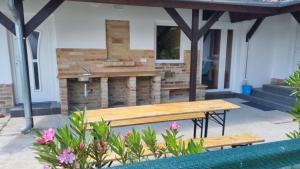 a picnic table in front of a house with a fireplace at ALFA Szálláshely in Sándorfalva