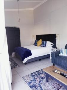 a bedroom with a bed and a couch at Dalau on Main in Paarl