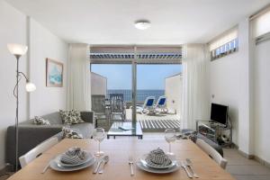een woonkamer met een tafel en uitzicht op de oceaan bij Casa Médano 19 By Médano Rentals in El Médano