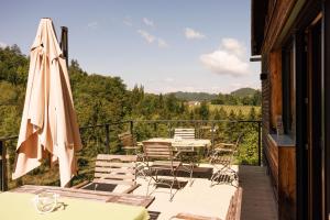 - un balcon avec des tables, des chaises et un parasol dans l'établissement Bauernhof Kure, à Leutschach