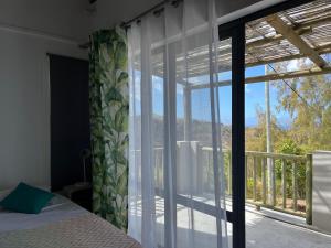 ein Schlafzimmer mit einem Fenster mit Blick auf einen Balkon in der Unterkunft COCO MANGO Villa in Trèfles