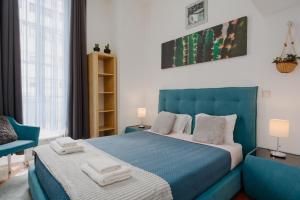 a bedroom with a blue bed and a chair at Ndussole Guest House in Porto