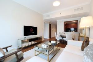 Chic 1BR Next to Dubai Marina Promenade by Livbnb في دبي: غرفة معيشة بأثاث أبيض وتلفزيون بشاشة مسطحة