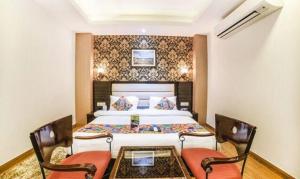 a bedroom with a bed with two chairs and a table at FabHotel Galaxy Patel Nagar in New Delhi