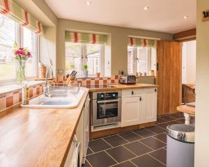 a kitchen with a sink and a stove top oven at Woodpecker Cottage in Blakeney