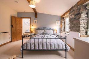 a bedroom with a bed and a stone wall at Woodpecker Cottage in Blakeney