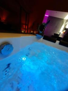 una bañera llena de agua azul en una habitación en Nuits Blanches, en Lieja