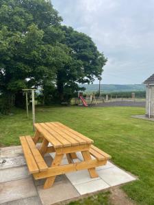 a wooden picnic table in a park with a playground at Branch cottage in Limavady