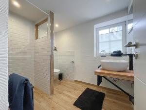 La salle de bains blanche est pourvue d'un lavabo et de toilettes. dans l'établissement Lüttjet Huus, à Lügde