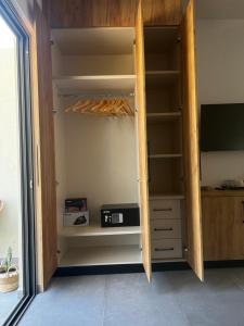 una camera con armadio, TV e scaffali di Sydney Hotel a Kefalos