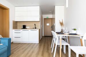 a kitchen and living room with a table and chairs at Aqua Apartment Šventovė, By Cohost in Palanga +27 photos