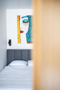 a bedroom with a bed with a painting on the wall at Aqua Apartment Šventovė, By Cohost in Palanga