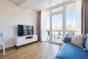 a living room with a tv and a blue couch at Aqua Apartment Šventovė, By Cohost in Palanga
