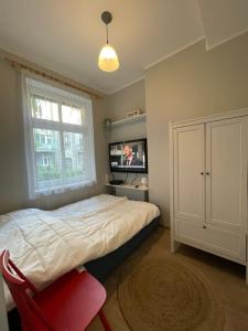 een slaapkamer met een bed en een tv en een rode stoel bij Home3city Przytulny in Sopot