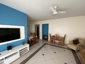 uma sala de estar com uma televisão de ecrã plano na parede em Apartamento Enseada Guarujá - 350m do Mar! no Guarujá
