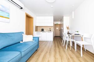a living room with a blue couch and a kitchen at Aqua Apartment Šventovė, By Cohost in Palanga